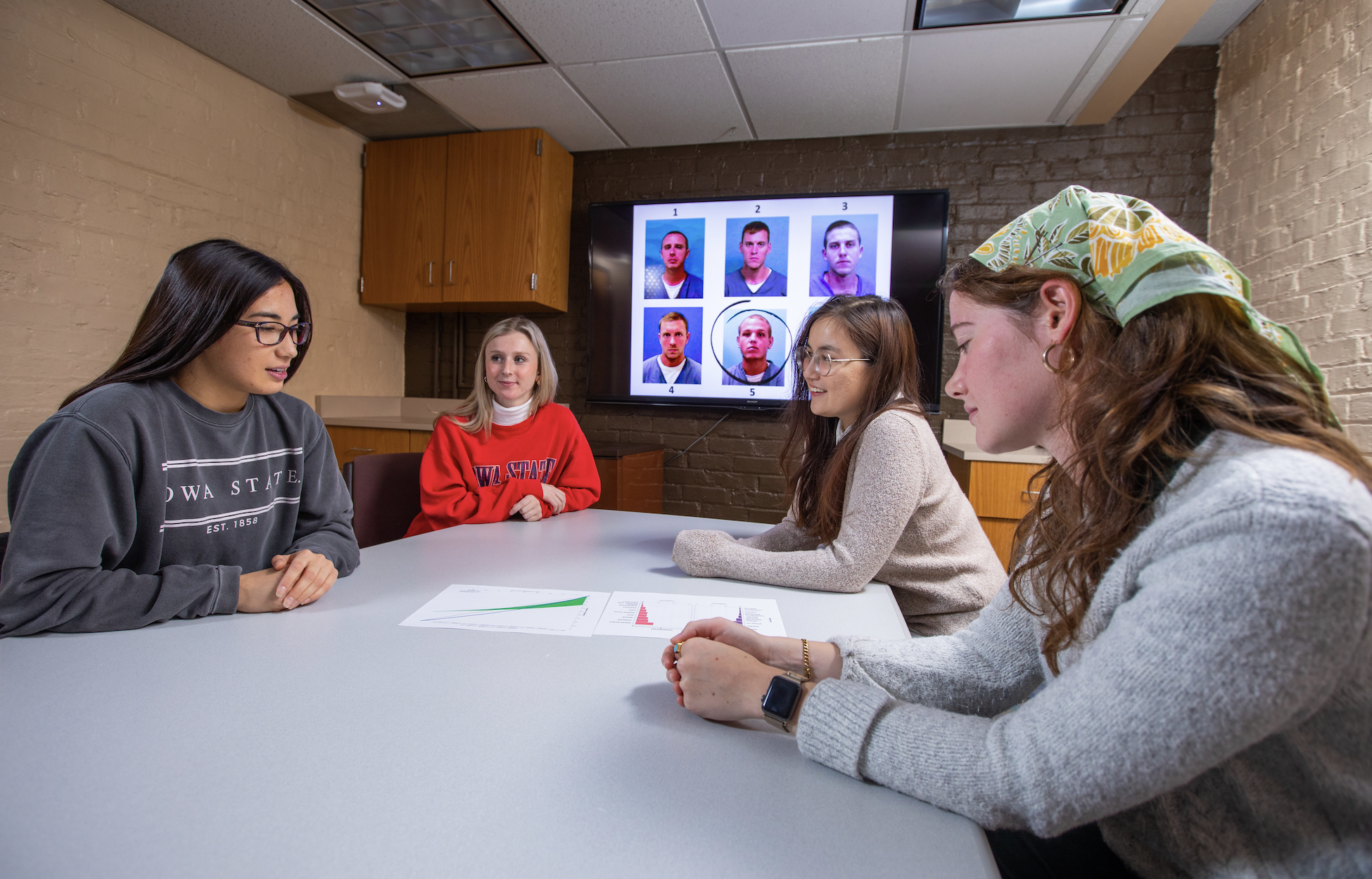 Four Psychology students reviewing research data at table